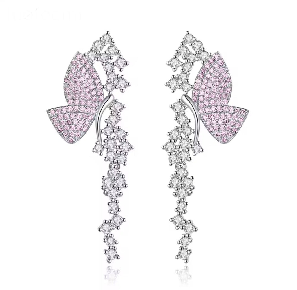 Pink pavé butterfly dangle earrings on a white background