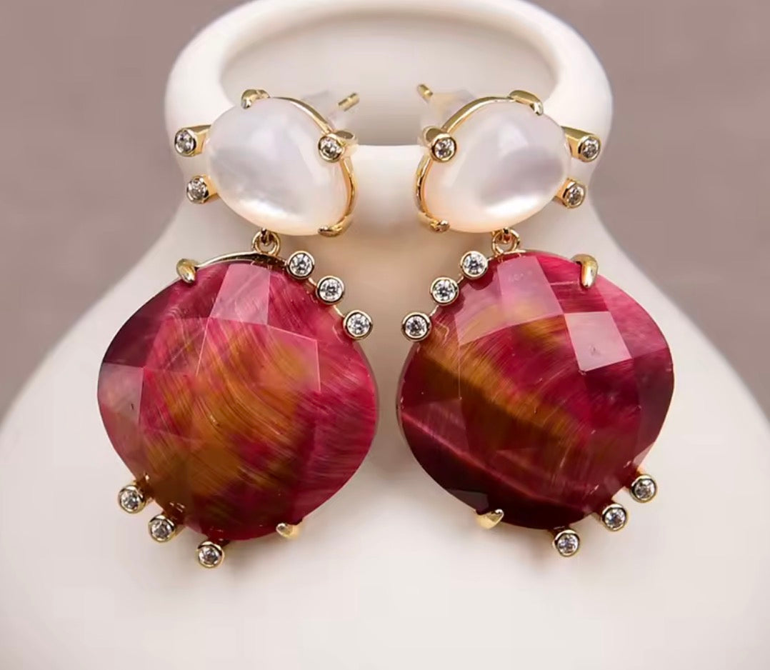 Fuchsia tiger eye and moonstone dangle earrings on a white display