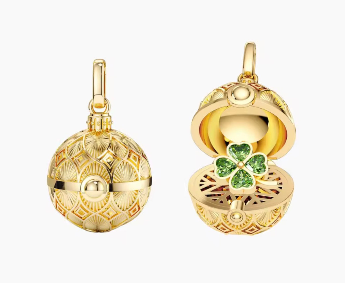 Gold globe charm necklace open to reveal a green four-leaf clover