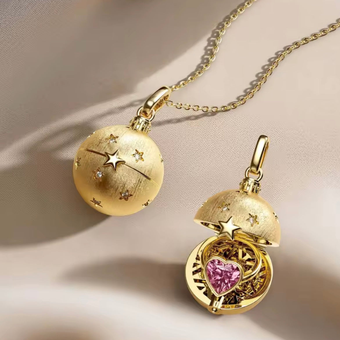 Gold globe charm necklace open to reveal a pink heart stone