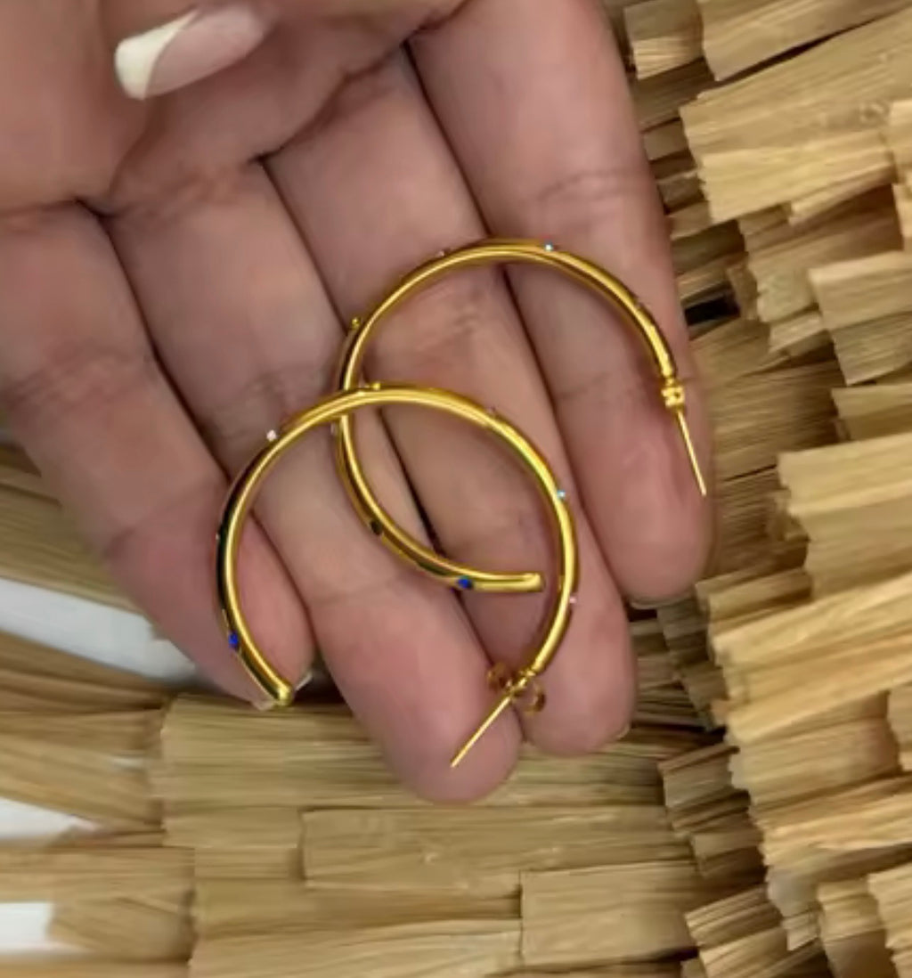 Gold hoop earrings shown in hand