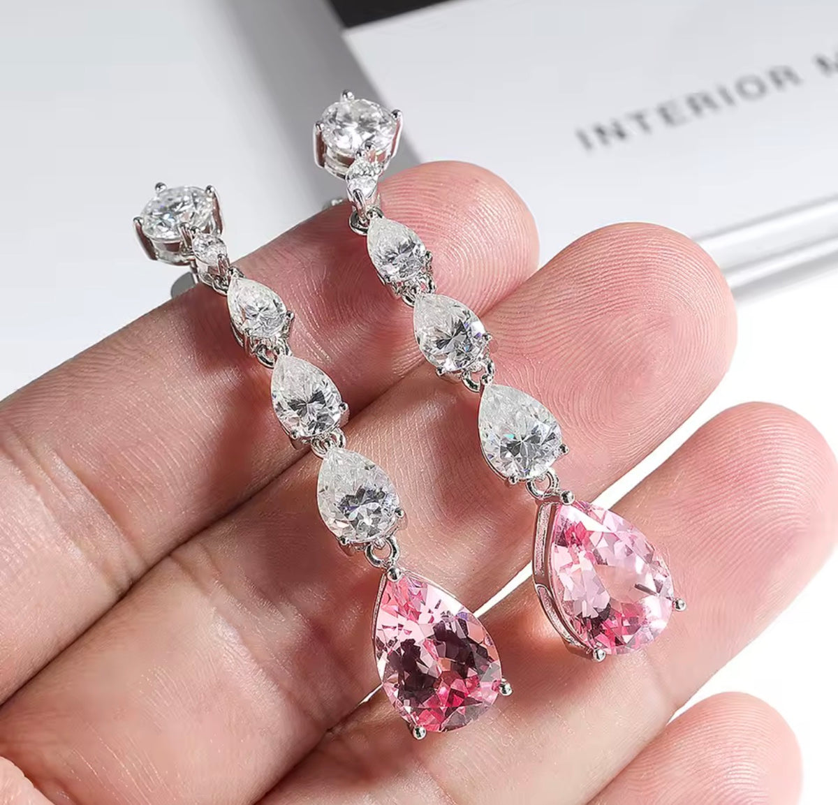Pink long dangle lab moissanite earrings shown in hand