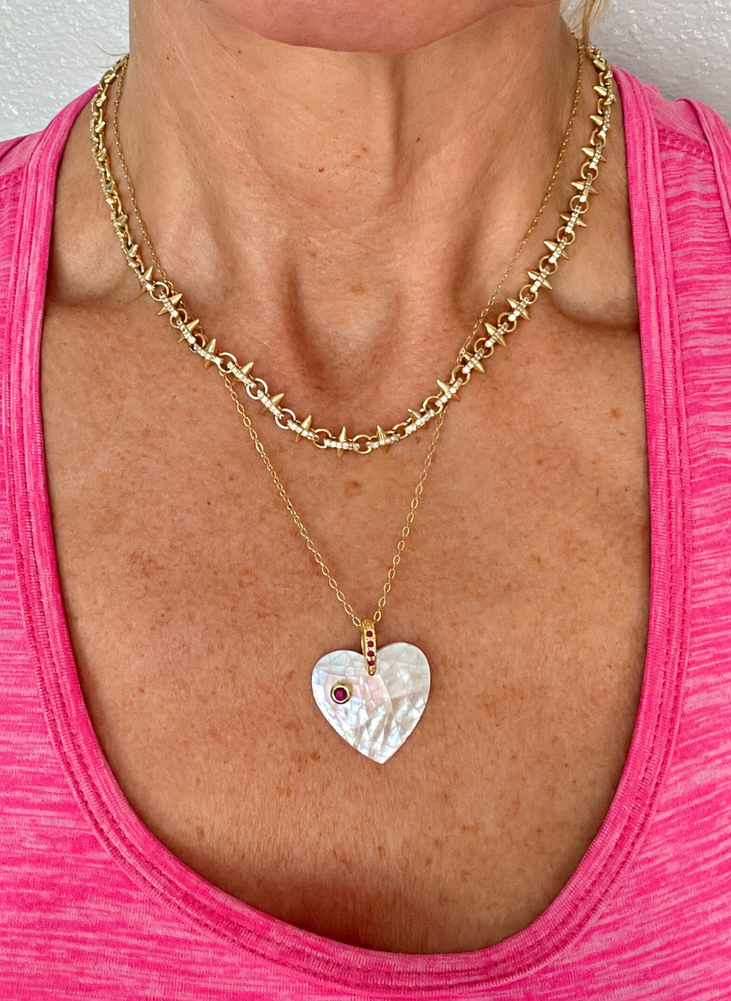 Brightened lifestyle photo of ruby mother of pearl heart necklace on pink shirt